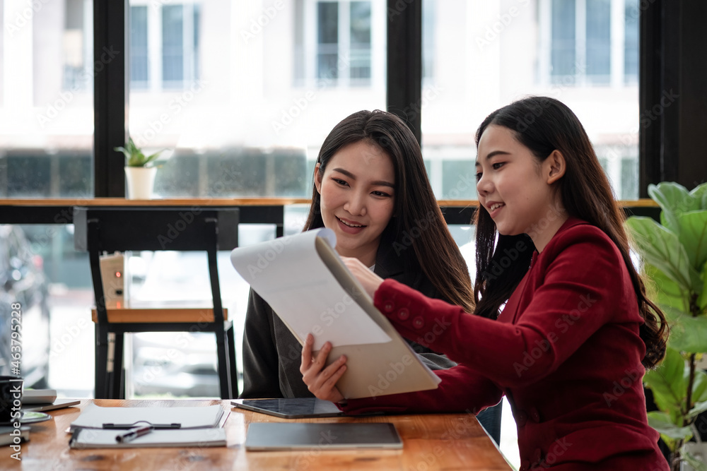 Business People Planning Strategy Analysis from financial document report, two asian female working together at office Business People Planning Strategy Analysis from financial document report, two asian female working together at office