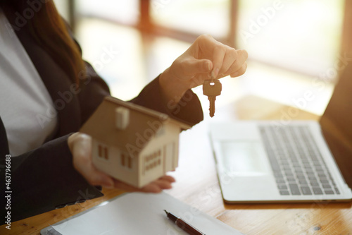 Φωτογραφία Female realtor broker holding home keychain and house model in her hand