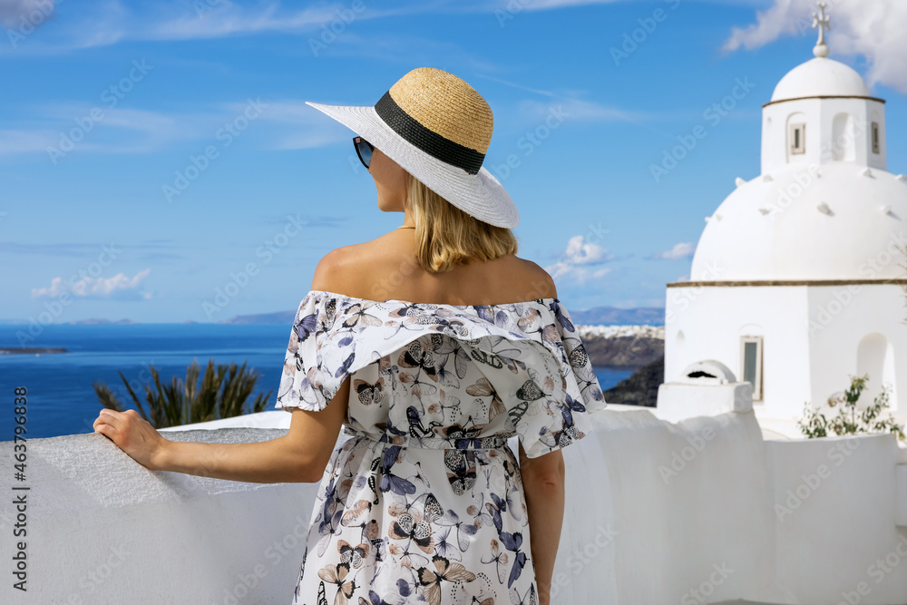 woman with straw hat and dress on summer vacation in Santorini island. Greece