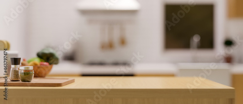 Fotografie Light wooden kitchen countertop with set of seasoning and space for montage over blurred kitchen background