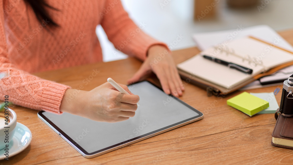 A female freelance graphic designer works on a digital tablet computer to create her graphics. A female freelance graphic designer works on a digital tablet computer to create her graphics.