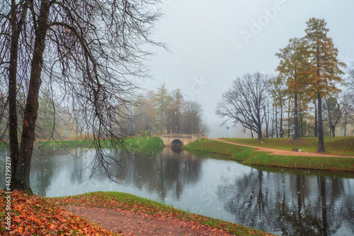 Foggy autumn landscape with first snow in State Museum Reserve Gatchina. Foggy autumn view of the park, Karpin Pond and old stone bridge. photo