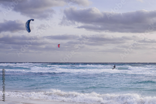 kitesurfers in the sky in the evening duck over the blue water of mediterranean sea