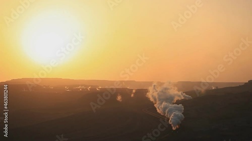 A steam train at sunset carrying coal loads runs on the Sandoling coal mine in the city of Hami in the northwest of Xinjiang Uygur Autonomous Region of China. photo