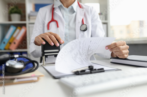 Doctor puts a stamp on medical documents closeup