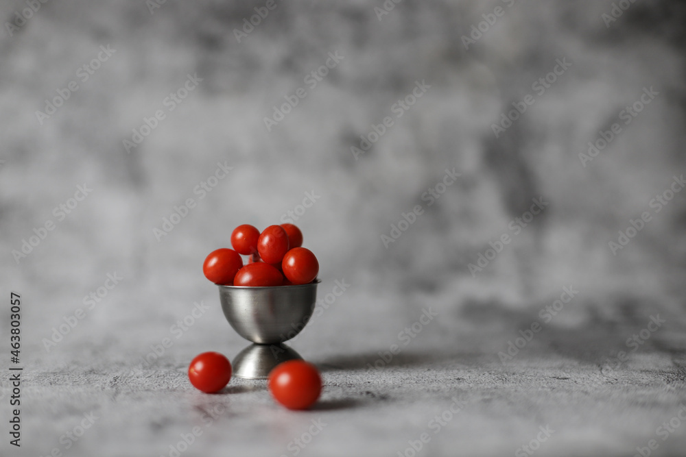Fototapeta premium Small red candy tomatoes in steel plate on grey background.