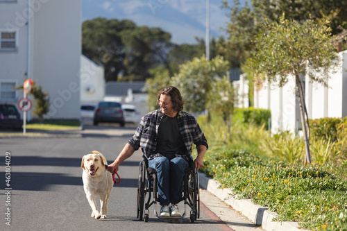 Caucasian disabled man with dog sitting on wheelchair on the road