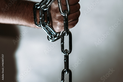 Hand with chain,The man's hand holds the iron chain,gray background.Copy space,selective focus.