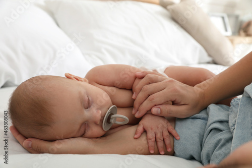 Mother with her cute baby sleeping in bed, closeup