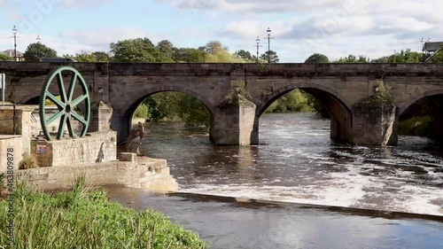 A beautiful old bridge going over the River Wharfe in the British town of Wetherby in Leeds, West Yorkshire in the UK, showing the stone brick bridge going in to the village on a hot sunny summers day photo