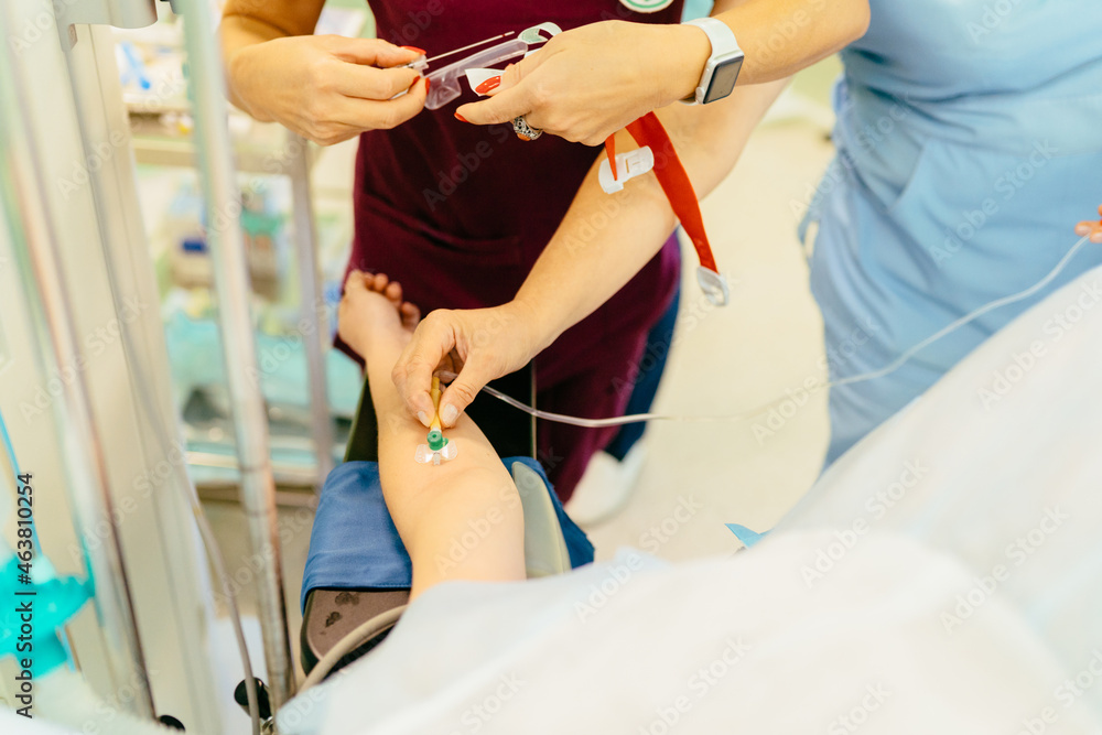 Obraz premium Block the pain. Close up of catheter with a syringe in hand of patient lying on an operating table. The process of surgery under general anesthesia. Preparation for caesarean.
