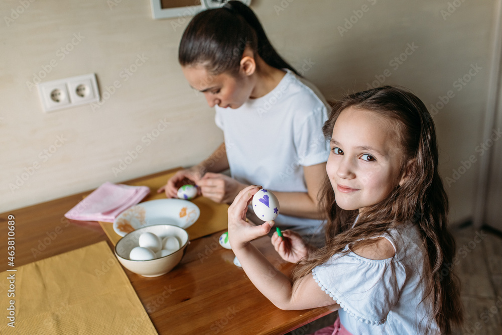 family traditions, mother and daughter at the table paint eggs for Easter family traditions, mother and daughter at the table paint eggs for Easter