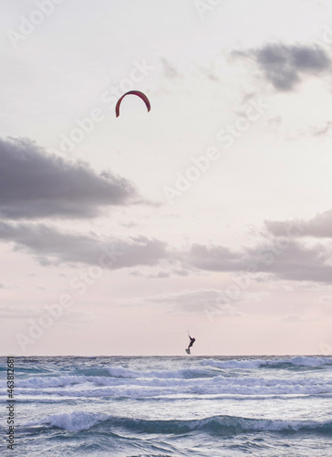 kitesurfers in the sky in the evening duck over the blue water of mediterranean sea