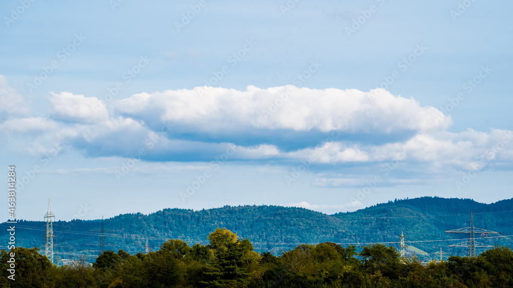 Panorama landscape, blue sky clouds over wooded hills, trees and power lines