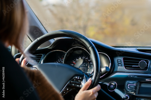 Croped woman hands of car driver on steering wheel, road trip, driving on a sunny day © Елена Бабанова