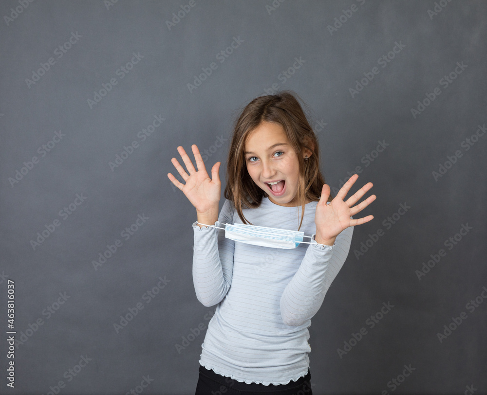 Portrait of young smiling girl giving up with medical mask on her hands on grey background. Portrait of young smiling girl giving up with medical mask on her hands on grey background.