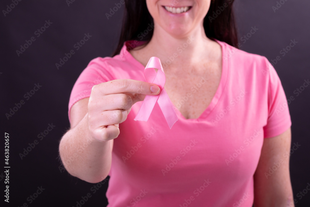 Midsection of happy caucasian woman in pink tshirt holding pink ribbon Midsection of happy caucasian woman in pink tshirt holding pink ribbon