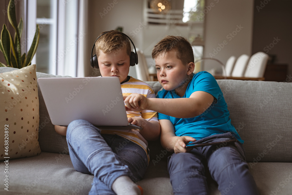 Two caucasian boys using laptop sitting on the couch at home Two caucasian boys using laptop sitting on the couch at home