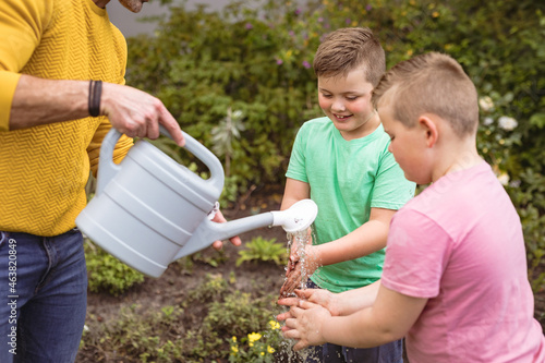 Caucasian father pouring water while two sons washing their hands in the garden