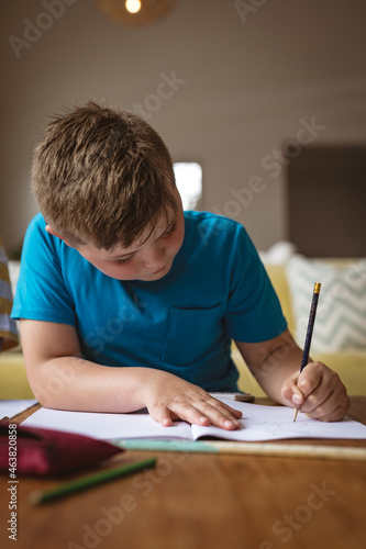 Caucasian boy drawing in his book sitting in the living room at home
