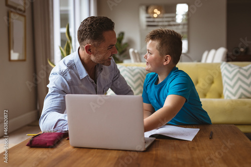 Caucasian father using laptop to help his son with homework at home