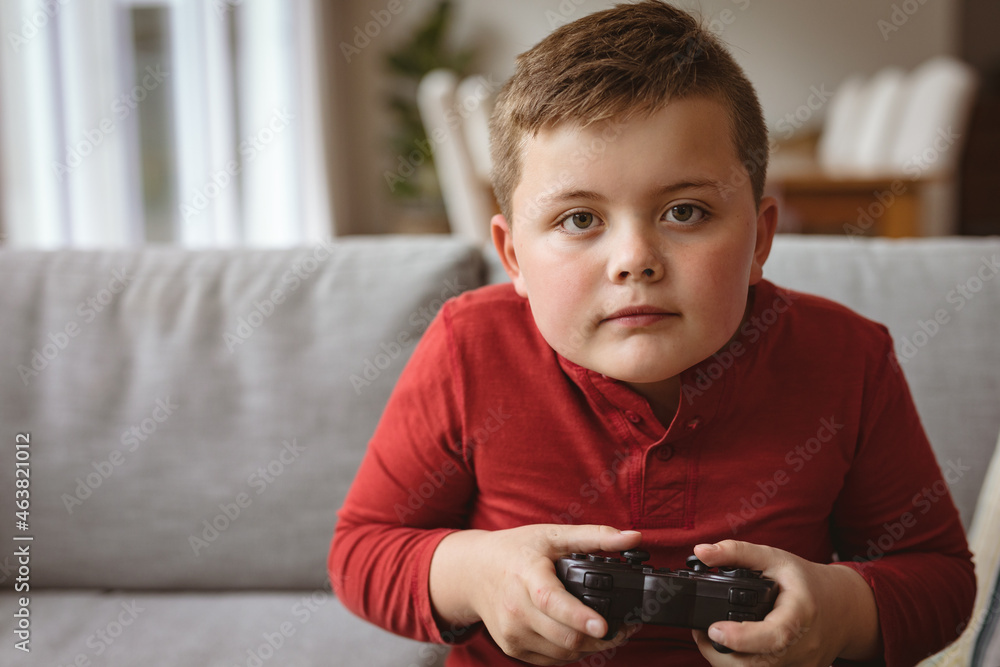 Caucasian boy playing video games sitting on the couch at home Caucasian boy playing video games sitting on the couch at home