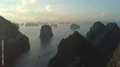 Scatter of rocky limestone islands full of tropical forests located on sea water of Ha Long bay at dawn as natural wonder in Vietnam