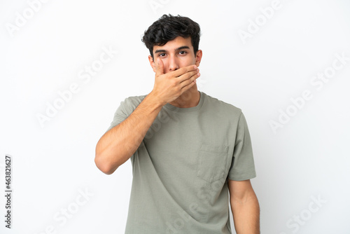 Young Argentinian man isolated on white background covering mouth with hand © luismolinero