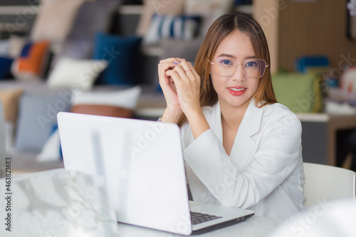 Young Asian professional business female wearing glasses works at co-working space with laptop paper work (Business woman concept).