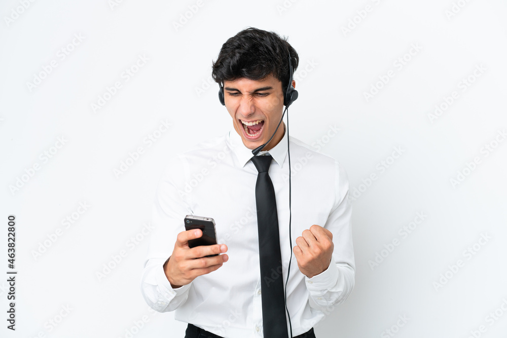 Telemarketer man working with a headset isolated on white background surprised and sending a message Telemarketer man working with a headset isolated on white background surprised and sending a message