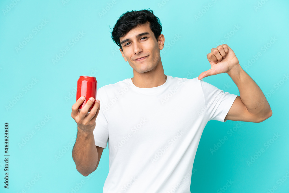 Young Argentinian man holding a refreshment isolated on blue background proud and self-satisfied Young Argentinian man holding a refreshment isolated on blue background proud and self-satisfied