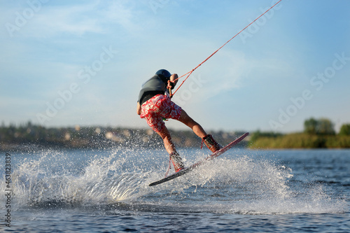 Teenage wakeboarder doing trick on river. Extreme water sport