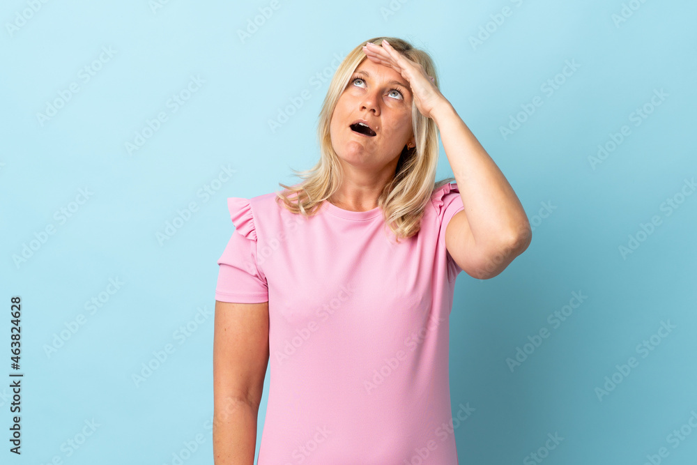 Middle age woman isolated on blue background doing surprise gesture while looking front Middle age woman isolated on blue background doing surprise gesture while looking front