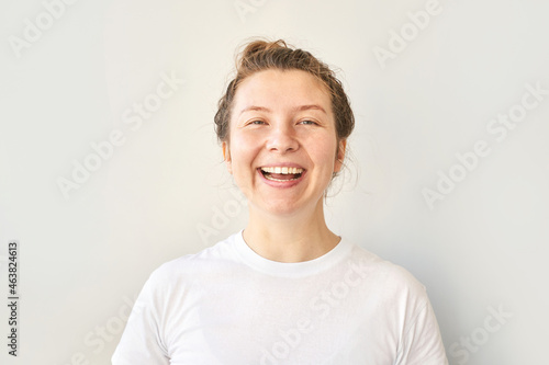 Young woman portrait. Pretty bussines face. Lifestyle happy emotions. White casual t-shirt. Looking at camera. Grey background. Copyspace. Adult people