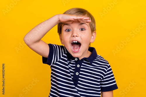 Photo portrait little boy wearing casual clothes staring amazed looking far hand near forehead isolated bright yellow color background