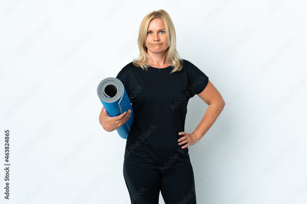 Middle age woman going to yoga classes while holding a mat isolated on white background with sad expression Middle age woman going to yoga classes while holding a mat isolated on white background with sad expression