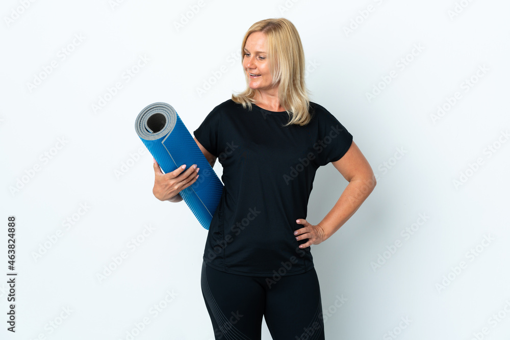 Middle age woman going to yoga classes while holding a mat isolated on white background with happy expression Middle age woman going to yoga classes while holding a mat isolated on white background with happy expression