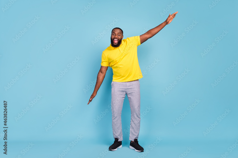 Photo of shiny pretty dark skin guy dressed yellow t-shirt smiling dancing isolated blue color background Photo of shiny pretty dark skin guy dressed yellow t-shirt smiling dancing isolated blue color background