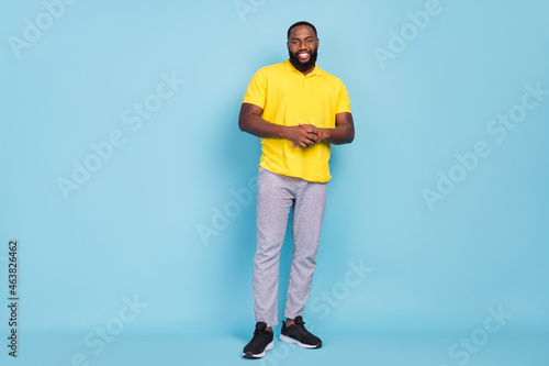 Photo of charming cute dark skin man wear yellow t-shirt standing smiling isolated blue color background © deagreez
