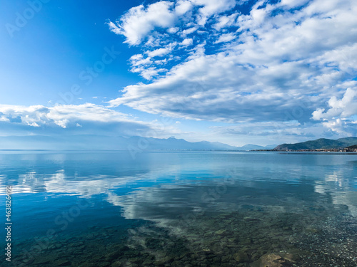 clouds reflection on the lake surface, natural colors, blue background © Oksana