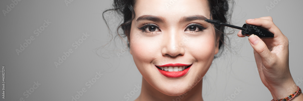 Beauty concept, asian woman with closed eyes holding mascara near eyes Beauty concept, asian woman with closed eyes holding mascara near eyes