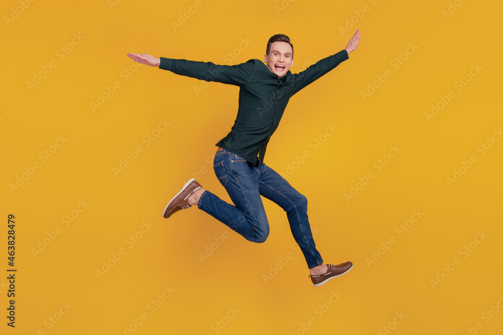 Full size profile side photo of young excited man have fun jumper fly wings plane isolated over yellow color background