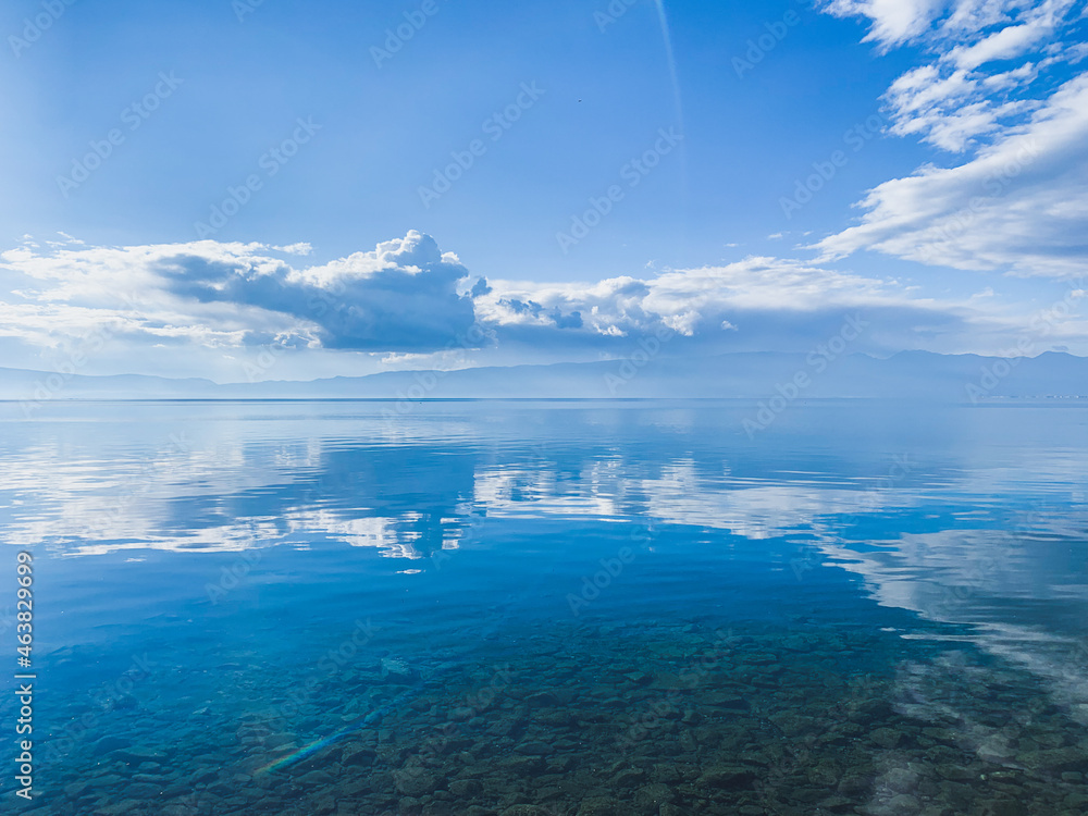 clouds reflection on the lake surface, natural colors, blue background