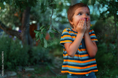 A child with a frightened face stands in the park