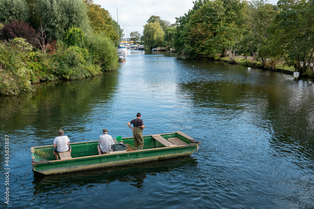 three men on a boat fishing on the River at Christchurch Dorset England