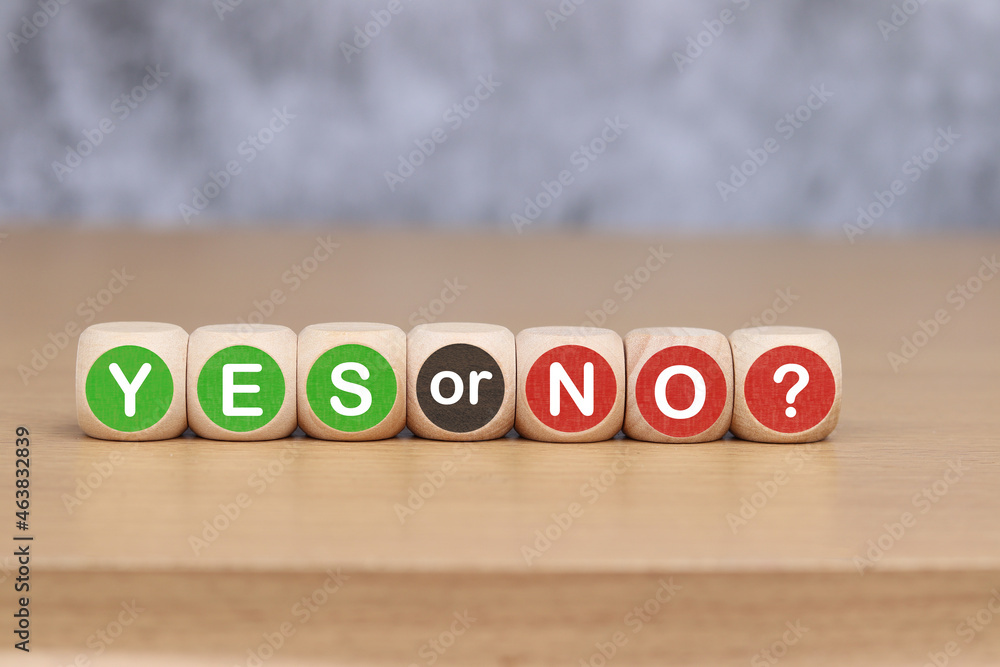 Wooden block with text YES or NO on wooden table background. Wooden block with text YES or NO on wooden table background.