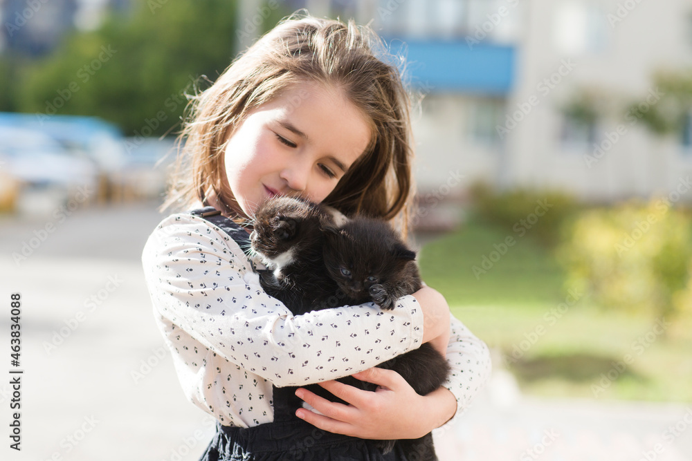 a child girl holds a small kitten in the street. animal from shelter a child girl holds a small kitten in the street. animal from shelter
