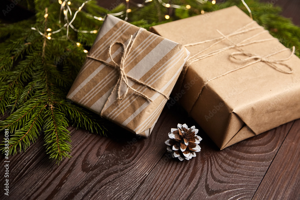 Gift boxes with Christmas light and tree branch with cone on brown wooden Gift boxes with Christmas light and tree branch with cone on brown wooden