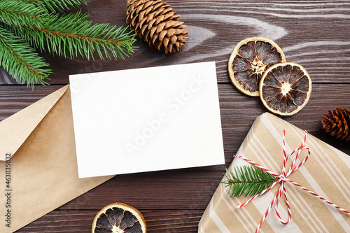 Christmas greeting card mockup with gift box, dry oranges, cones and fir tree branches