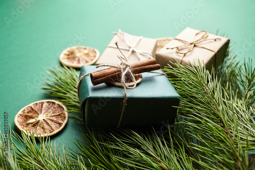 Christmas gift boxes and pine tree branches with decoration on green